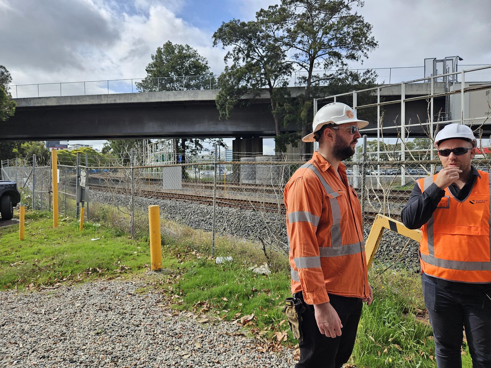 Media (12) Two surveyors in hi-vis discussing setout beneath a rail bridge